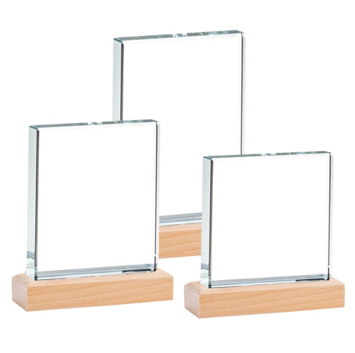 Three clear glass frames on wooden bases against a white background